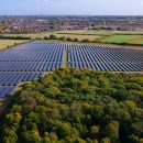 Aerial view of a large solar farm with solar panels in a green landscape.