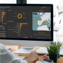 Man working on desktop computer at home, mockup blank screen monitor for product display or graphic design. Panoramic office background.